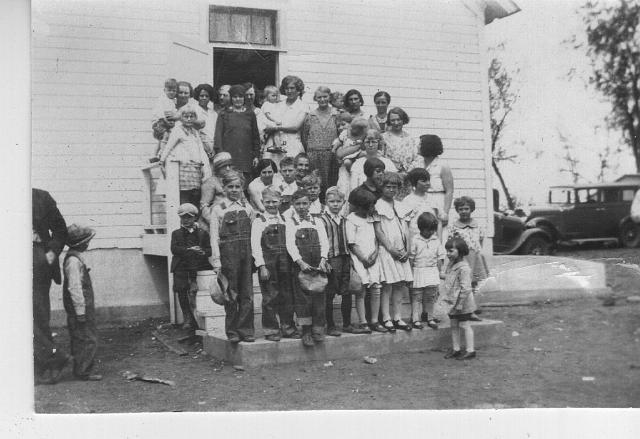 students_yordy_school_1930.jpg - the last day of the school year at the Yordy school in 1930 showing the students and their families;Robert Joseph Bowles is in the front row, holding his hat with both hands and wearing a bowtie; his mother Ella Bowles and grandmother Virginia Bowles are standing on the top steps